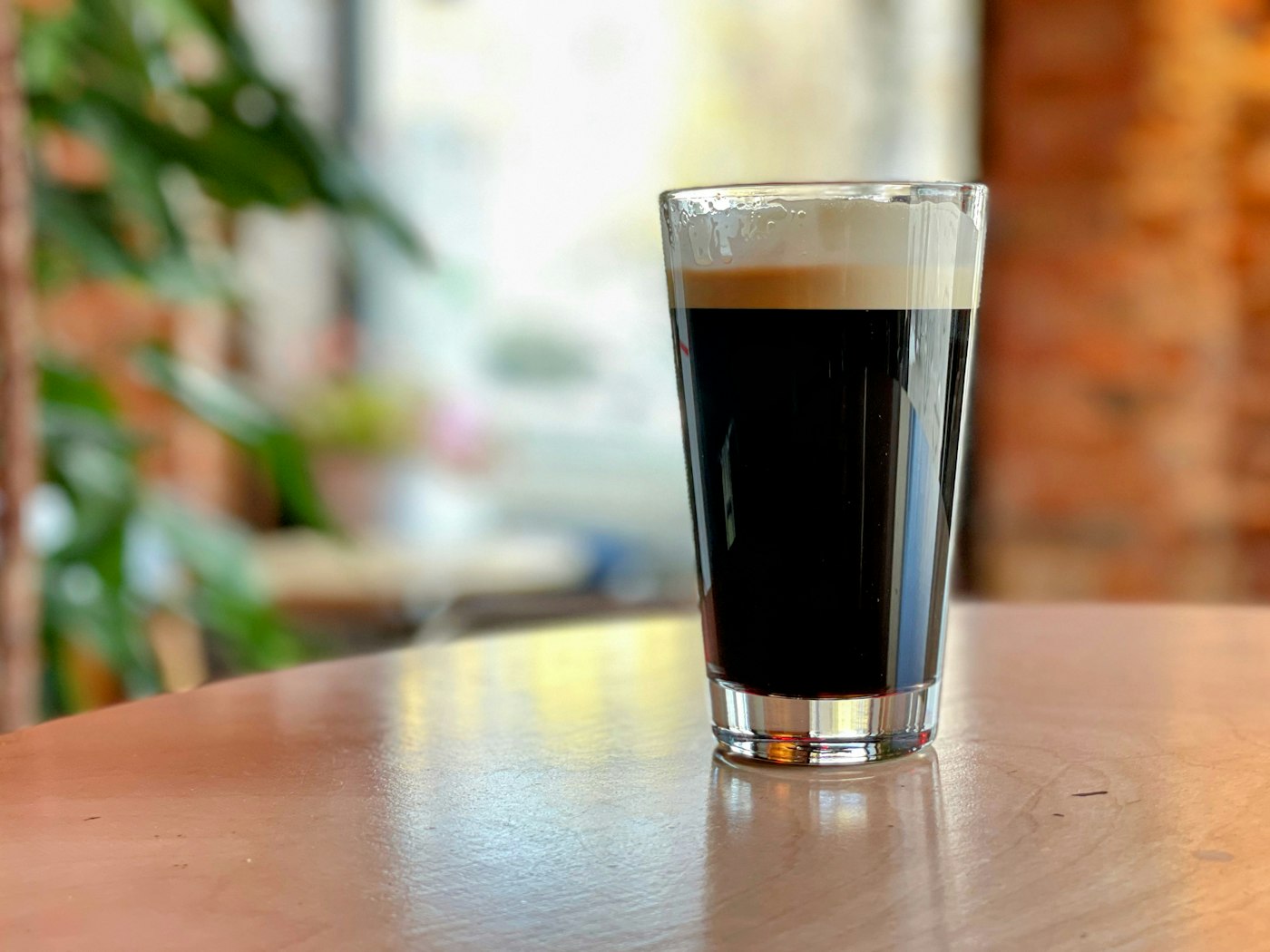 A pint of black stout with a tan head on a pale table