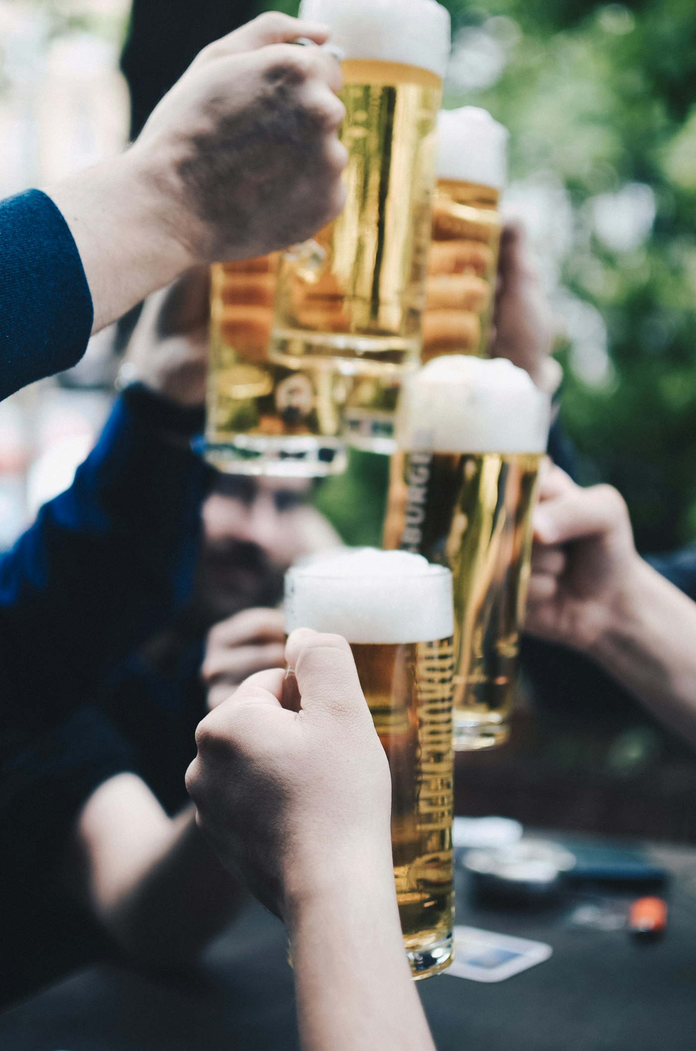 Friends toasting with four foamy gold beer mugs