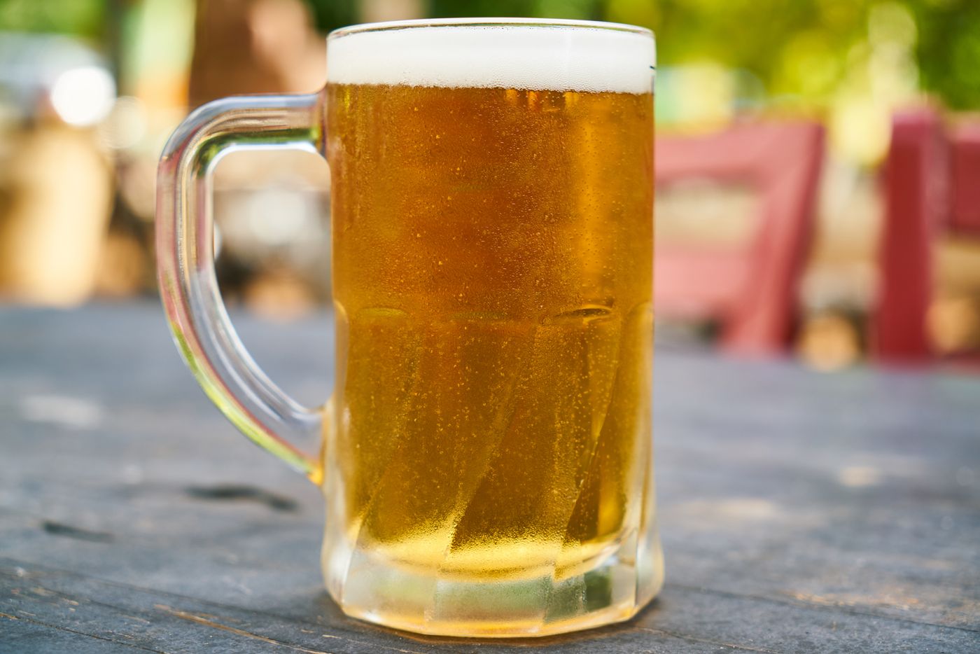 A golden beer mug on a picnic table in soft daylight