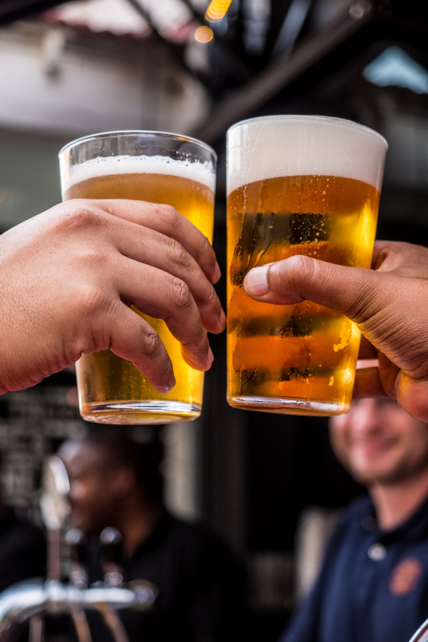 Two pale-gold pints meeting in a toast