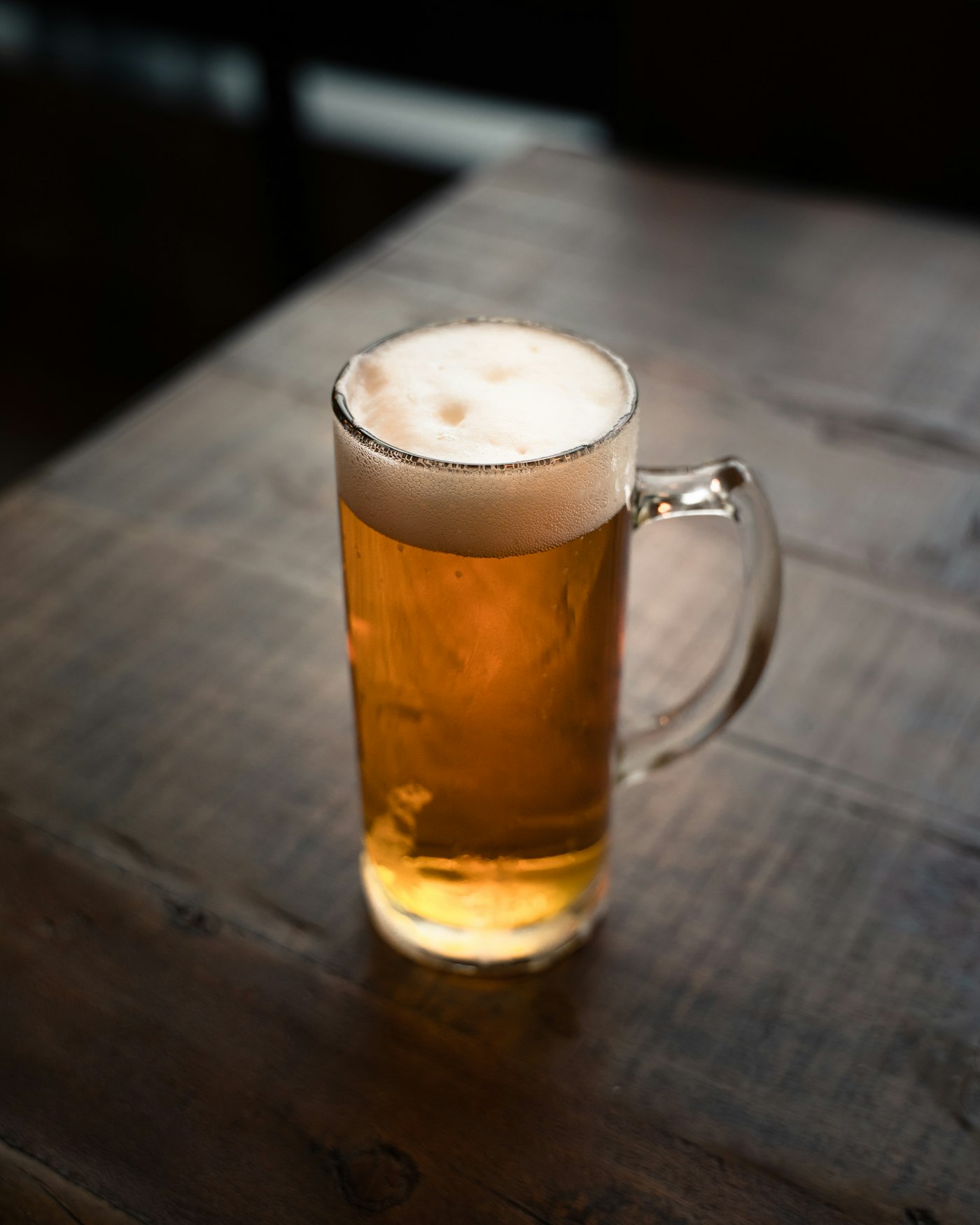 An amber beer mug sitting alone on a dark wood table
