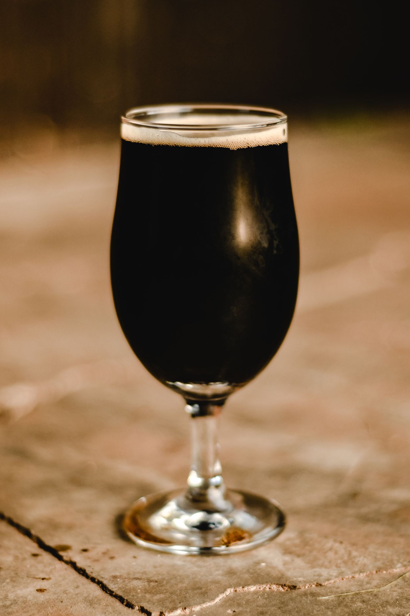A tulip glass of near-black porter on stone
