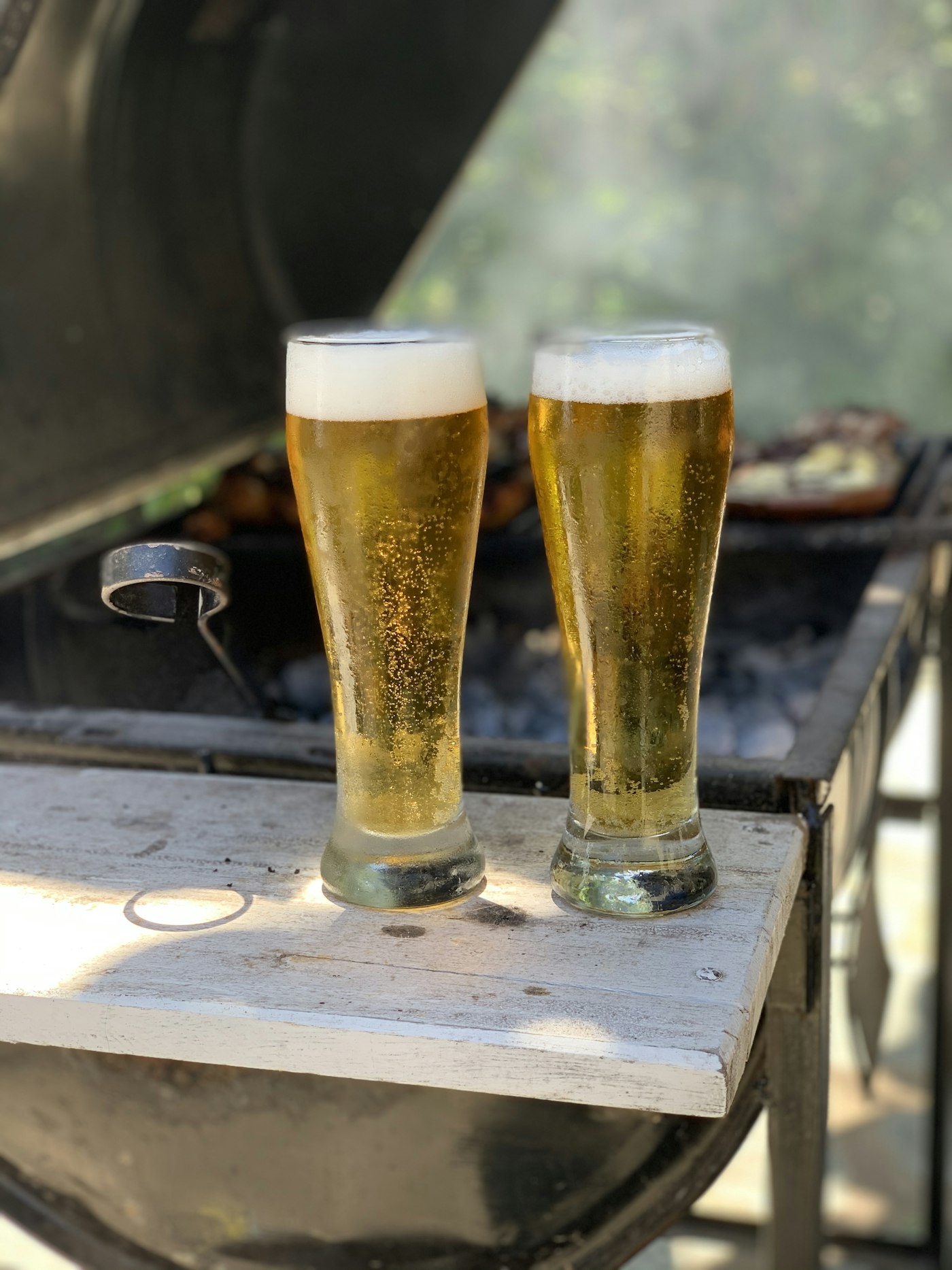 Two tall pale-gold pilsners with white foam